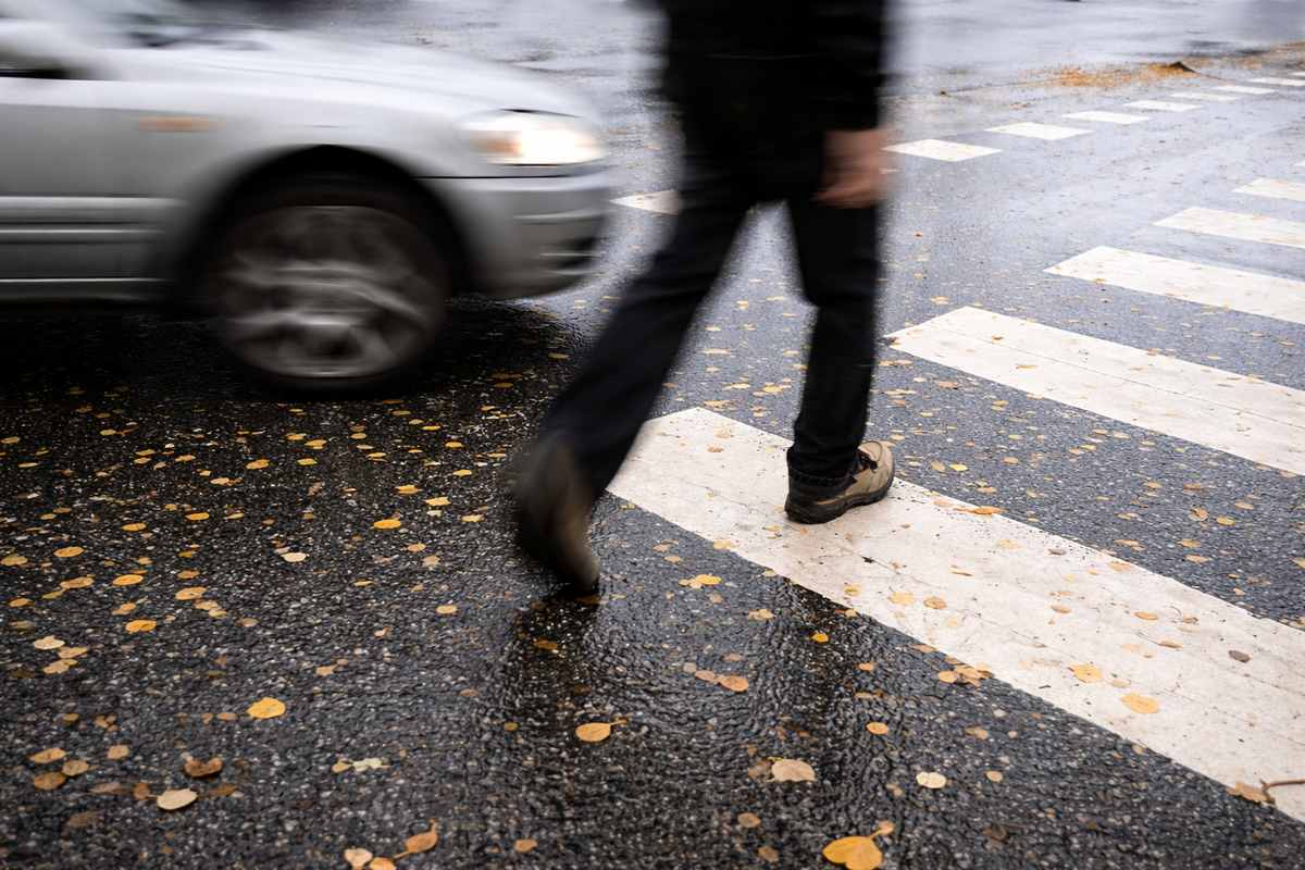 Abogado para accidentes de peatones: peatón cruzando la calle mientras un vehículo se aproxima en un cruce peatonal