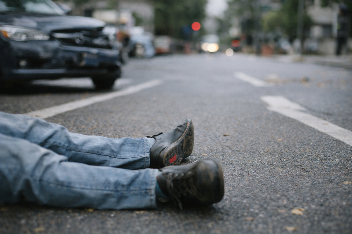 peatón herido acostado en la carretera después de un accidente de tráfico con vehículos al fondo