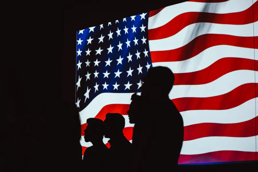 Siluetas de una familia frente a la bandera de Estados Unidos, representando ayuda legal de asilo y protección migratoria con J Kelley Law Group
