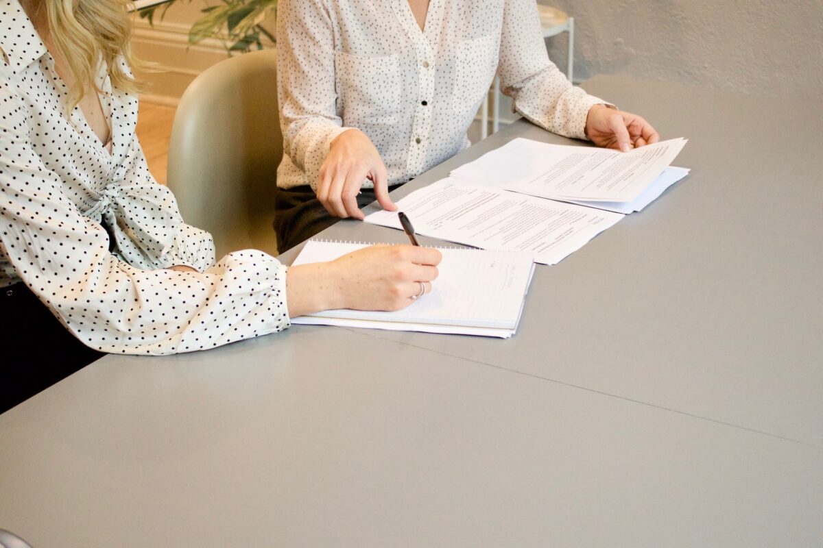 Two professionals reviewing documents and notes, representing adjustment of status case preparation and legal process support at J Kelley Law Group