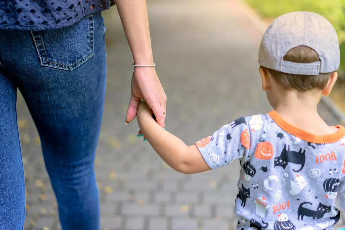 Adulto caminando de la mano con un niño, representando asuntos de custodia de menores en Maryland.