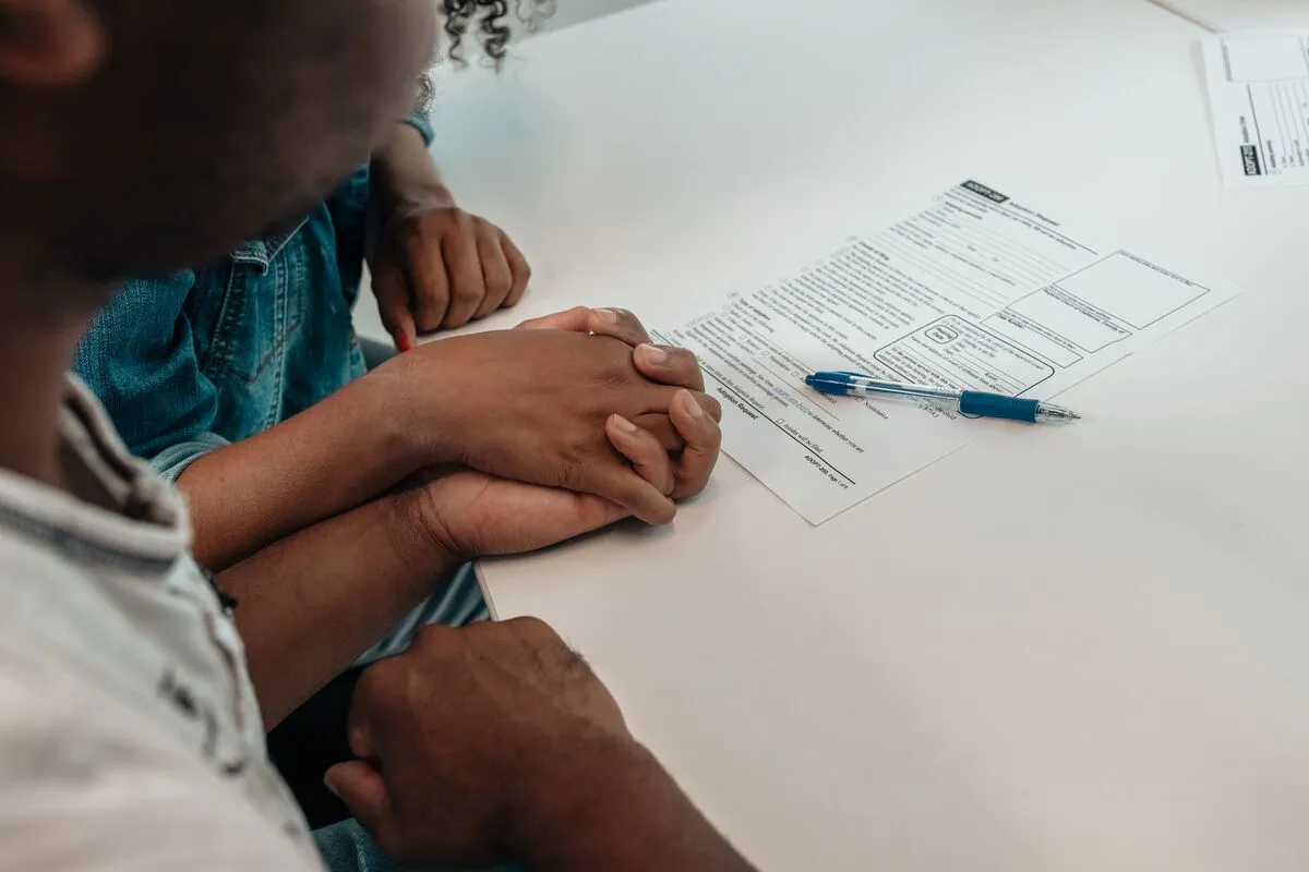 Familia tomada de las manos junto a documentos de inmigración durante una consulta sobre asilo con J Kelley Law Group