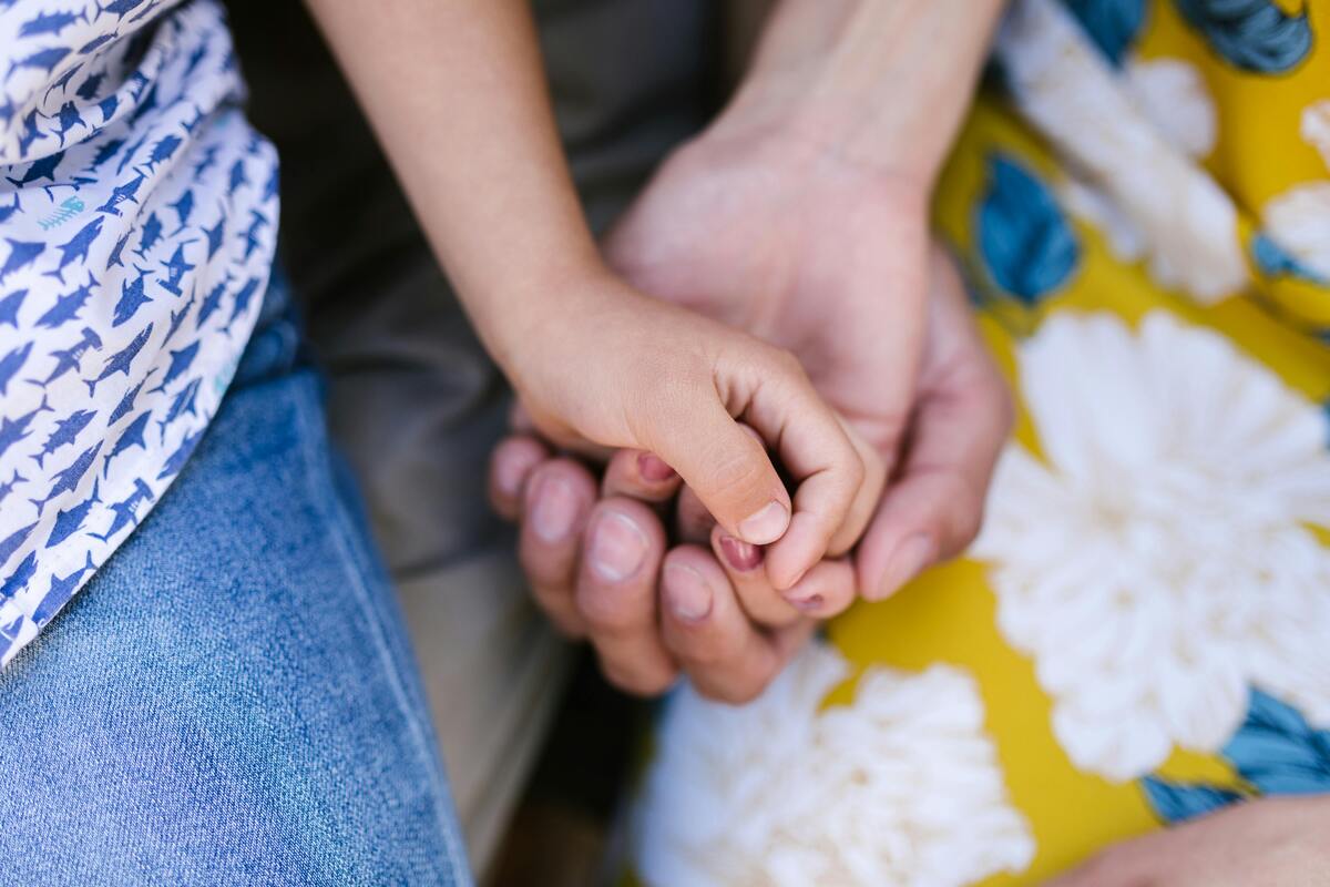 Adult hands gently holding a child’s hand, representing protective SIJS custody legal support for children and families in Maryland.