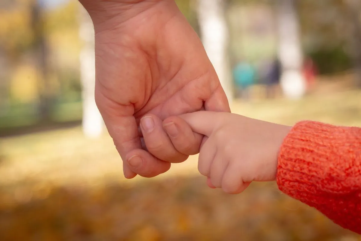 Mano de un adulto sosteniendo la mano de un menor, representando orientación legal en custodia de menores para familias en Maryland con J Kelley Law Group